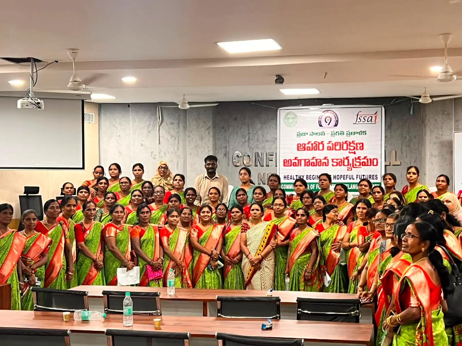 Large group of participants gathered in a hall beneath a banner for a food safety awareness programme.